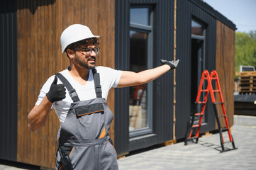 Construction worker supervising modular house placement on truck