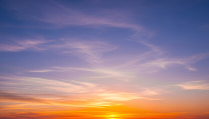 Fototapeta premium Colorful sunset sky with scattered clouds glowing in orange, yellow, and soft blue shades, creating a soothing natural gradient ideal for calm visual compositions or headers.