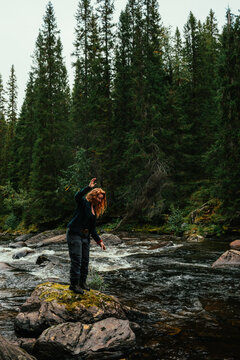 Young hiker woman balancing on mossy rock in a river in hotagen,