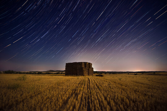 Stars tracing the celestial equator over a pile of hay bales