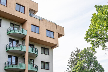 Obraz premium Modern Apartment Building with Balconies and Trees in a Residential Urban Neighborhood