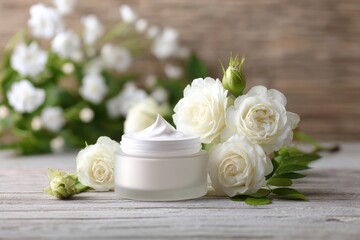 A glass jar of creamy white moisturizer sits amongst several pristine white roses and greenery on a rustic wooden surface