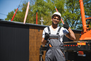 Construction worker supervising lifting of modular house onto truck