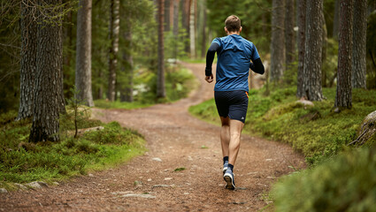 Man jogging in green forest trail