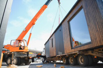 Crane lifting prefabricated modular house onto truck for transportation