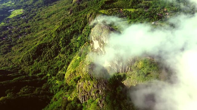 An aerial view shows steep rock cliffs towering amidst lush tropical forest with white mist shrouding the peaks in Sukoharjo, Central Java, Indonesia, on Sunday, June 8, 2025.