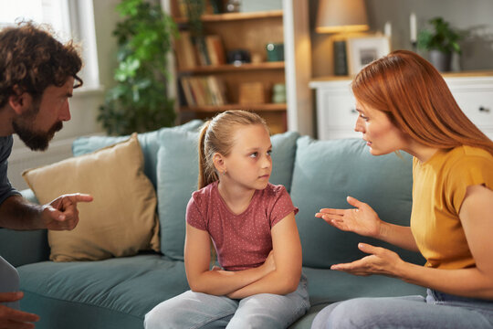 Parents communicate with their child regarding her behavior while seated in a comfortable living room, creating a serious yet constructive atmosphere for open dialogue.
