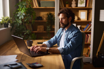 In a warm and inviting home office, a man is engaged in focused work on his laptop, surrounded by...