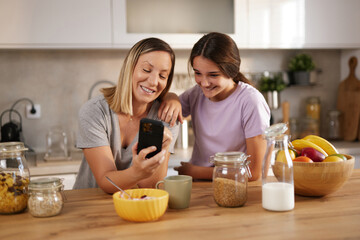 Mother and daughter enjoy a delightful interaction while checking something on a smartphone. They...