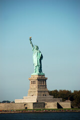 Obraz premium The Statue of Liberty standing tall on Liberty Island in New York City, captured on a clear, sunny day with a blue sky background