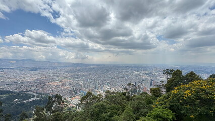 Fototapeta premium Cityscape of Bogotá Seen from Monserrate Hill with Foreground Greenery, Colombia