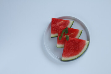 Stacked watermelon slices with mint on white plate and background