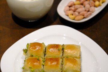 Traditional Turkish pistachio mini square baklava close-up. Pistachio baklava. Turkish syrup desserts. Ramadan, iftar menu. Sliced mini baklavas on a white plate. Turkish desserts.
