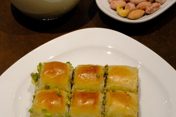Traditional Turkish pistachio mini square baklava close-up. Pistachio baklava. Turkish syrup desserts. Ramadan, iftar menu. Sliced mini baklavas on a white plate. Turkish desserts.
