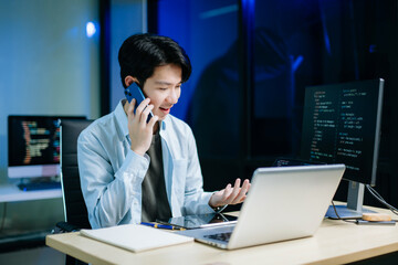 Asian software developer working late with code on screens, tablet, and phone. Concept of...