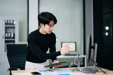 Asian businessman analyzing charts with a digital pen on tablet. Perfect for stock themes in finance, data, productivity, business analytics
