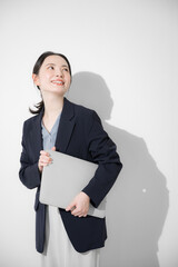 Business image of a young pretty woman standing with a computer, looking at the camera, upper half...