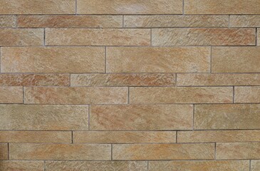 Elegant beige stoneware wall with stone effect. Long rectangle tiles with different sizes. Exterior...