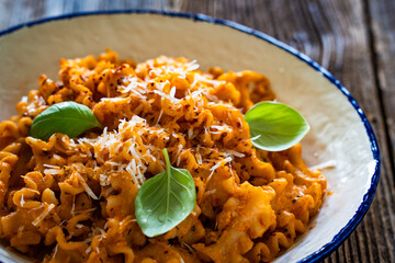 Creamy tomato and stracciatella reginelle noodles on wooden table
