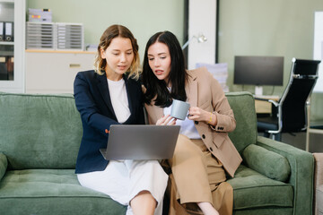 Two businesswomen collaborate using a tablet in a stylish office setting. Perfect for concepts