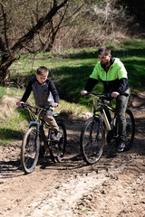 Obraz premium Father and son enjoy a sunny bike ride on a muddy trail.
