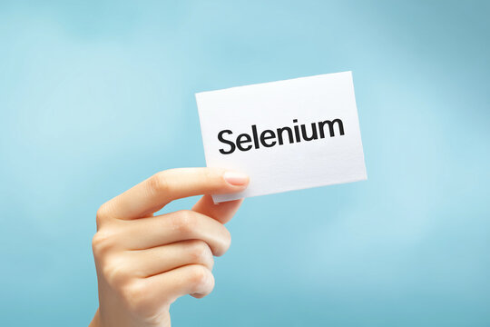 Close-up of female hand holding white sign with text 'Selenium' on light blue.