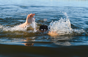Man drowning in water, reaching for help in open lake