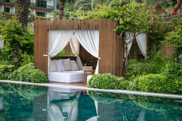 Loungers with white curtains and pool view 