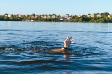 Man drowning in a lake is raising hand asking for help