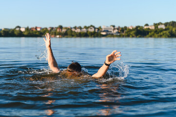 Man drowning in a lake is raising his arms and asking for help