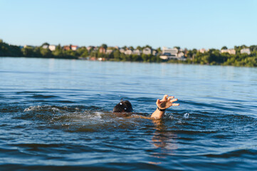 Man drowning in lake reaching for help on sunny day