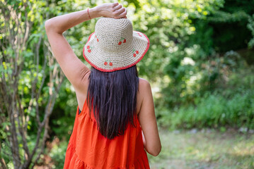 Woman with red dress and straw hat in the summer nature 
