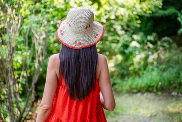 Woman with red dress and straw hat in the summer nature 