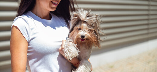 Unrecognizable woman hugging her yorkie dog outdoor 