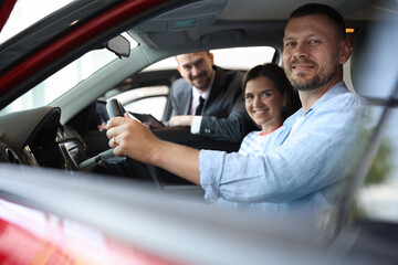 Salesman showing new car to happy family, selective focus