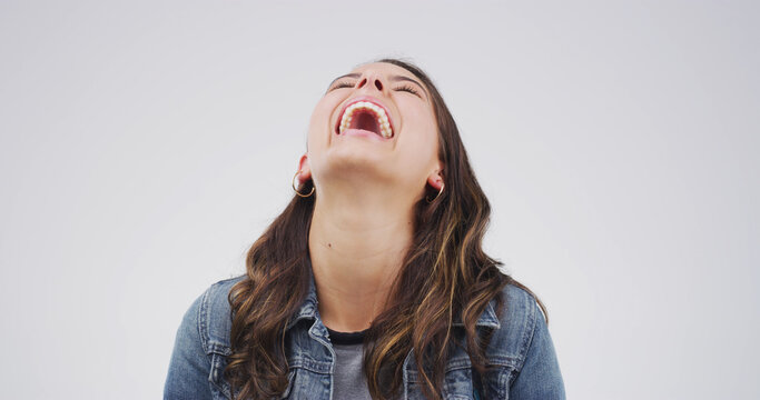 Laughing, funny and comedy with woman in studio for comic expression, joke and goofy. Positive mindset, happiness and meme reaction with person on white background space for humor and good mood