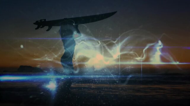 Surfing footage showing sunset causing light trails around surfer silhouette stepping toward shore