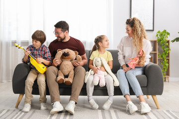 Obraz premium Children and their parents playing with different toys on sofa at home