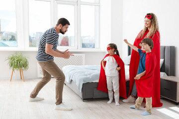 Parents and children in superhero costumes playing at home