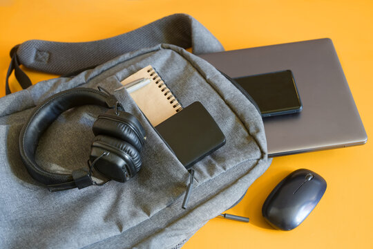 Compact backpack featuring tech essentials for students or travelers. Ideal for studying, music, or work with a yellow background. Photo. High resolution