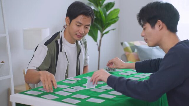 Asian young men poker players playing casino card game together in house. 