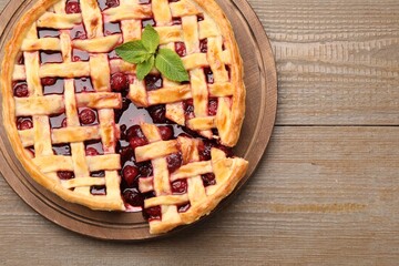 Tasty cut cherry pie on wooden table, top view. Space for text