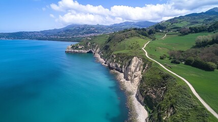 Coastal cliffs meet a turquoise sea, grassy hills rise above