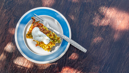 Delicious vegetable casserole topped with sour cream rests on a plate outdoors, showcasing vibrant colours in natural light