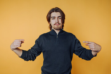 Confident young man pointing at himself against a bright yellow background during a casual indoor...
