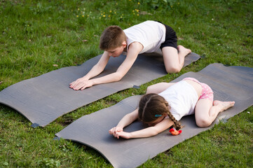 Children practicing yoga outdoors on mats. Healthy active lifestyle.