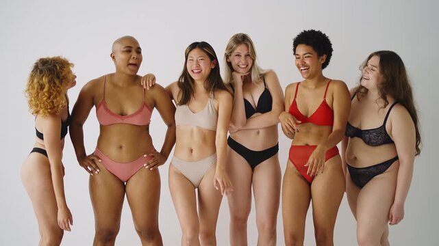 women in underwear are laughing and hugging each other, celebrating body positivity and female friendship against a white background