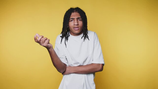 young man stands with arms crossed, displaying a puzzled expression on yellow background