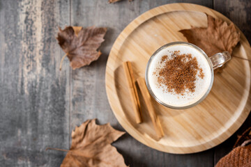 Maple Latte with Cinnamon in Glass Mug on wooden table. Copy space