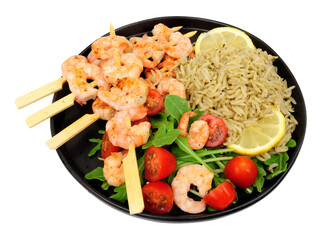 Grilled king prawn skewers meal with wholegrain basmati rice and wild rocket leaves and tomato salad isolated on a white background